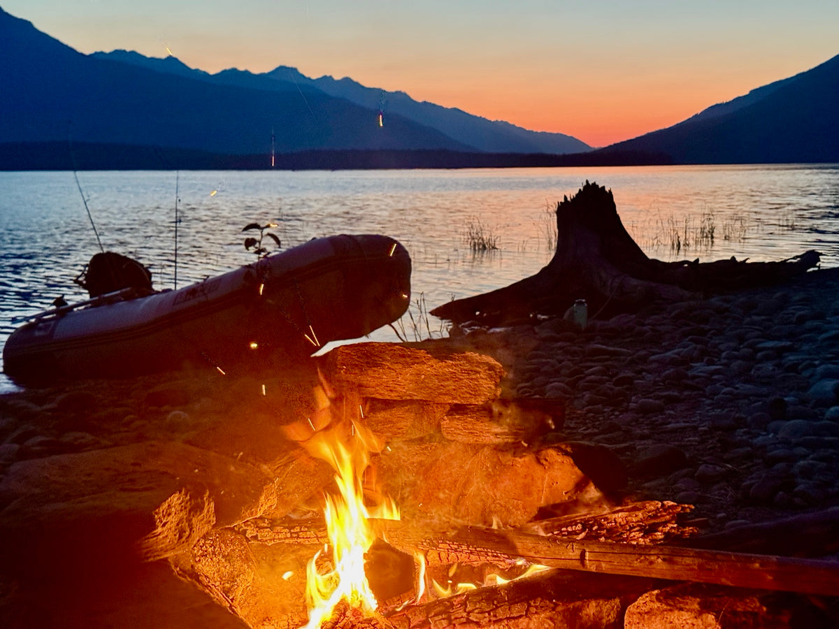 Campfire and boat on the shore of Kinbasket Lake